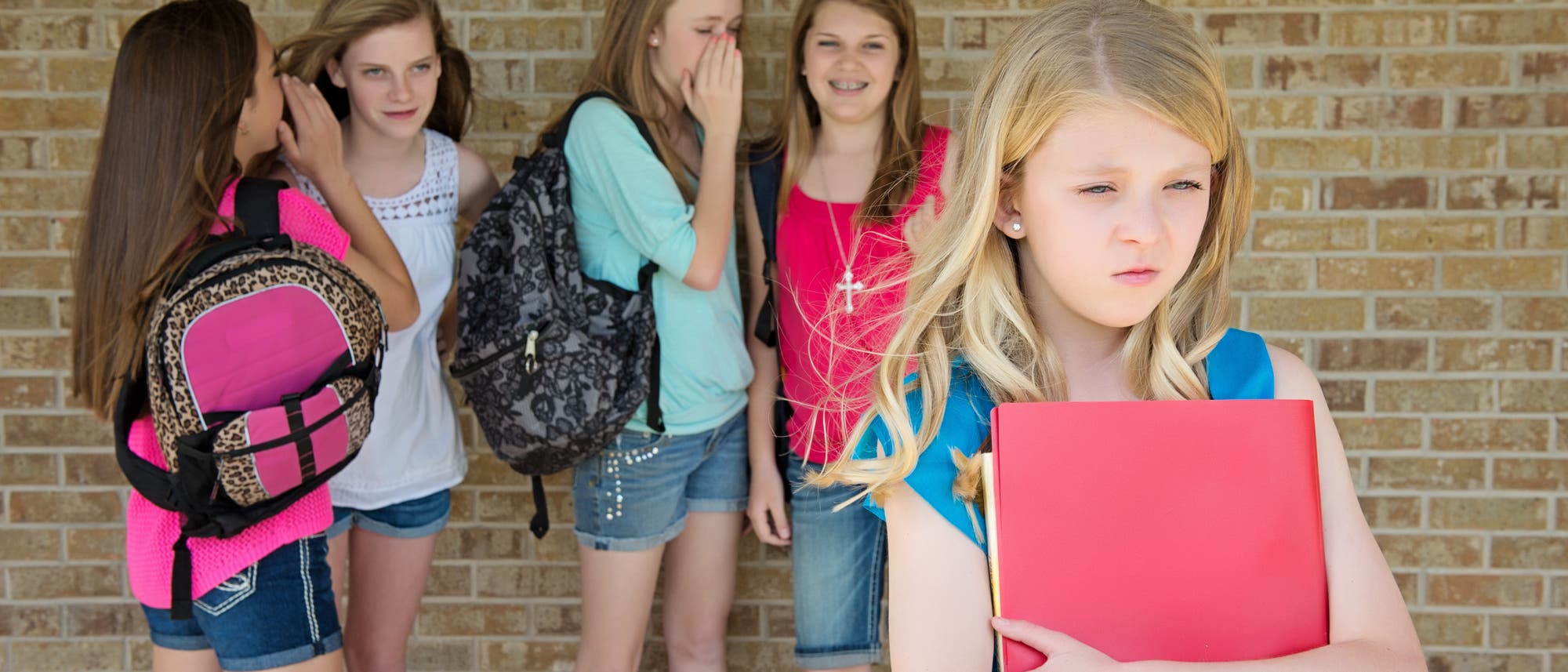 Mädchen tuscheln über Mitschülerin: Sexuelle Gewalt kann auch auf verbaler Ebene stattfinden
