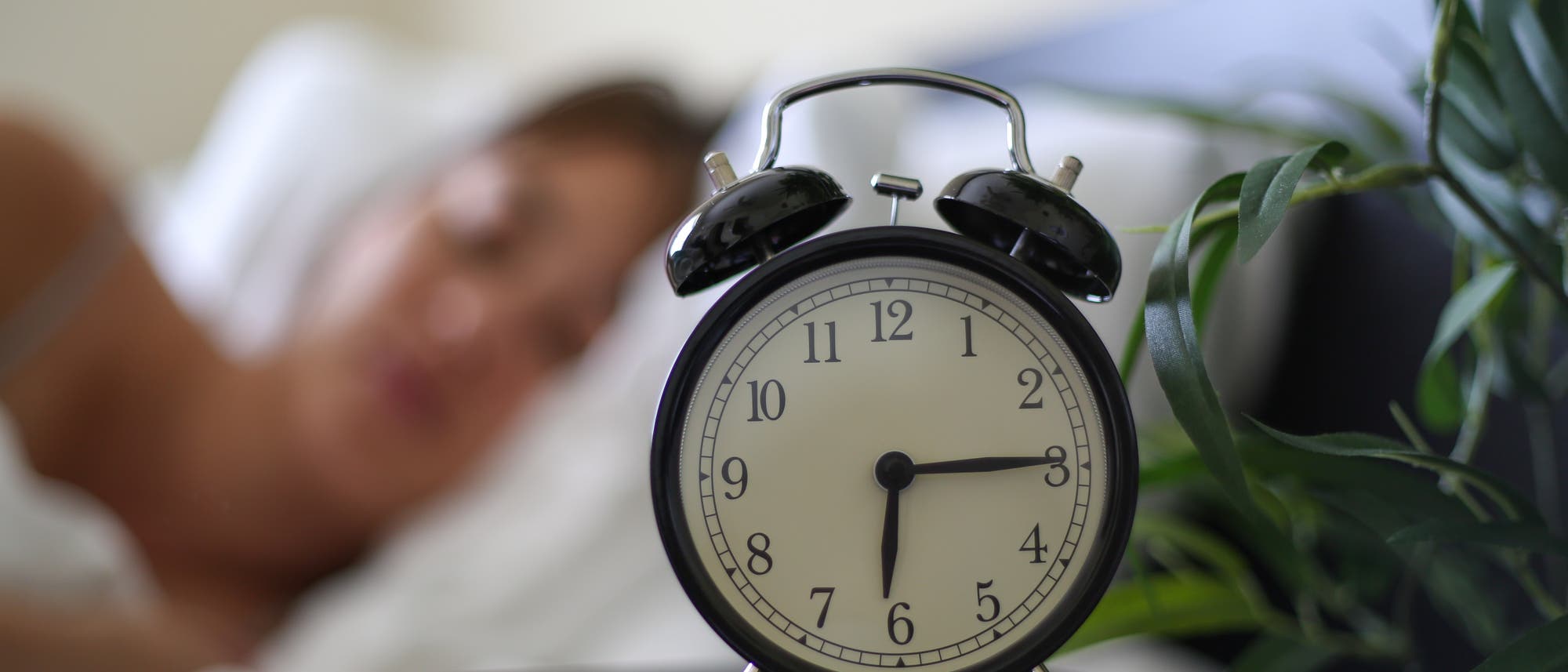 Wecker am Bett zeigt die Uhrzeit: Viertel nach sechs