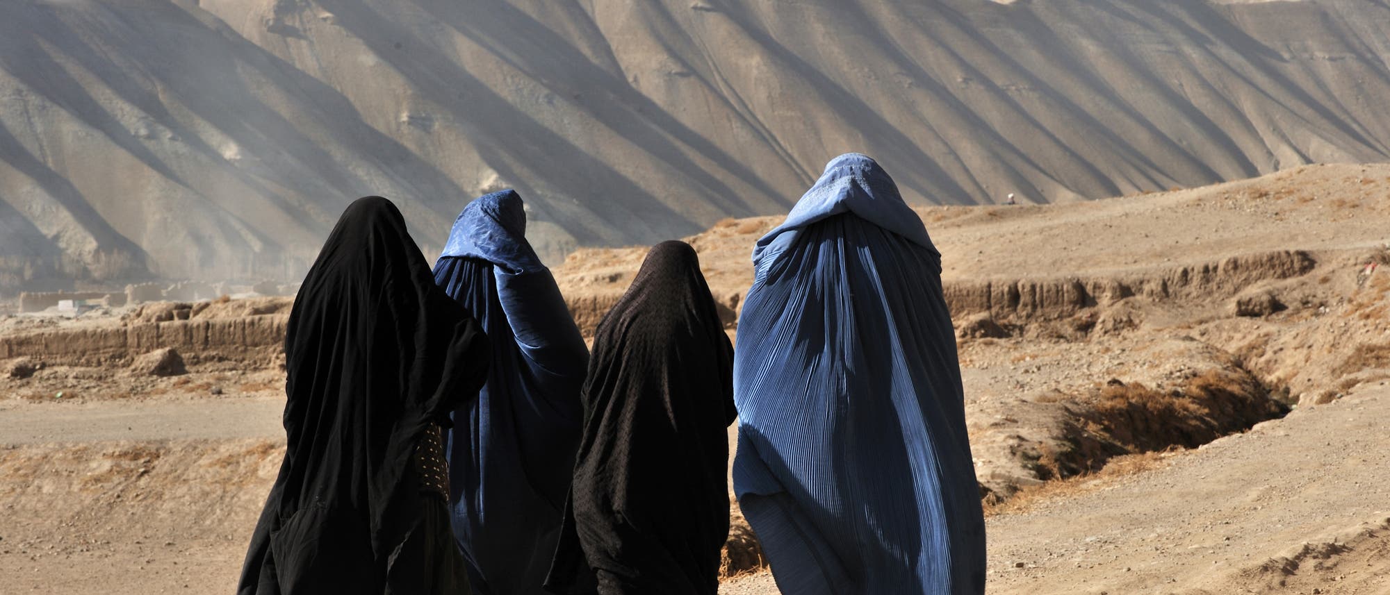 Vier verhüllte Frauen in der afghanischen Wüste
