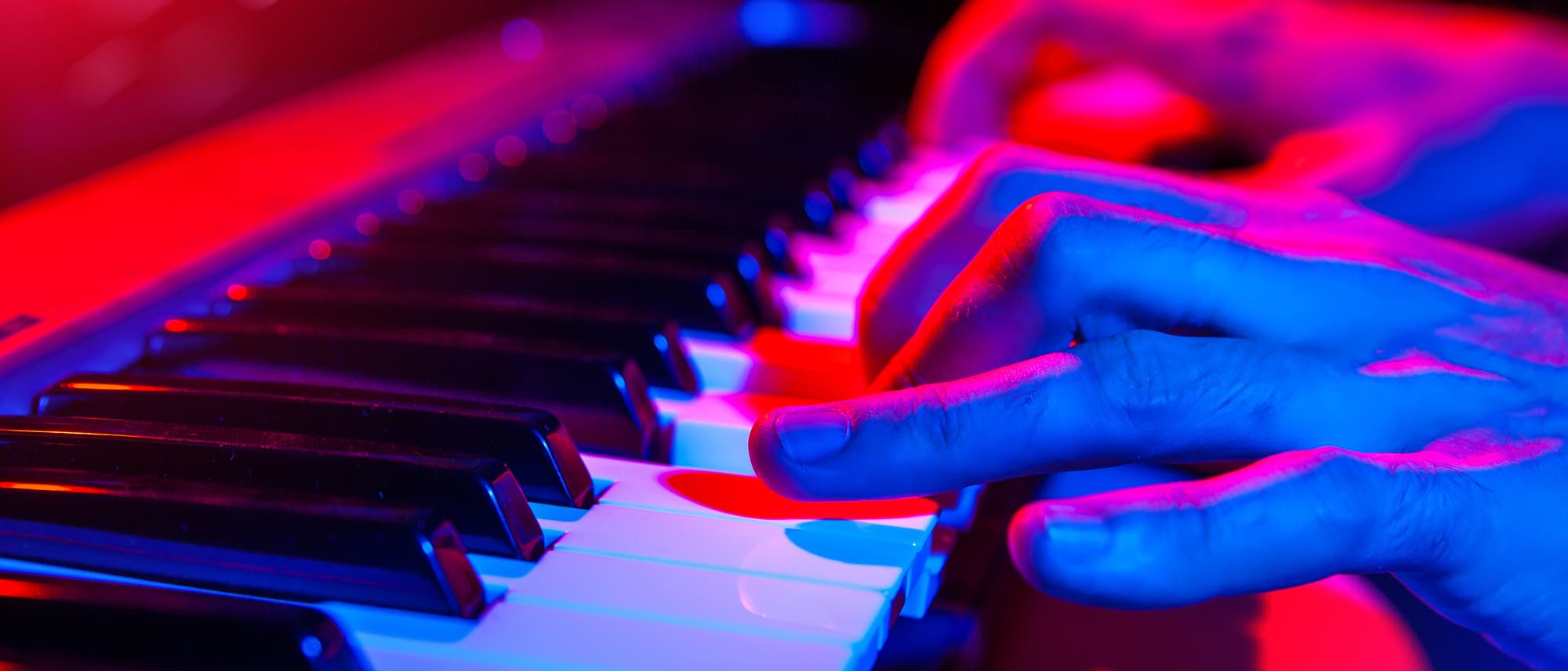 Farbig angeleuchtete Hände am Klavier Farbig angeleuchtete Hände am Klavier
