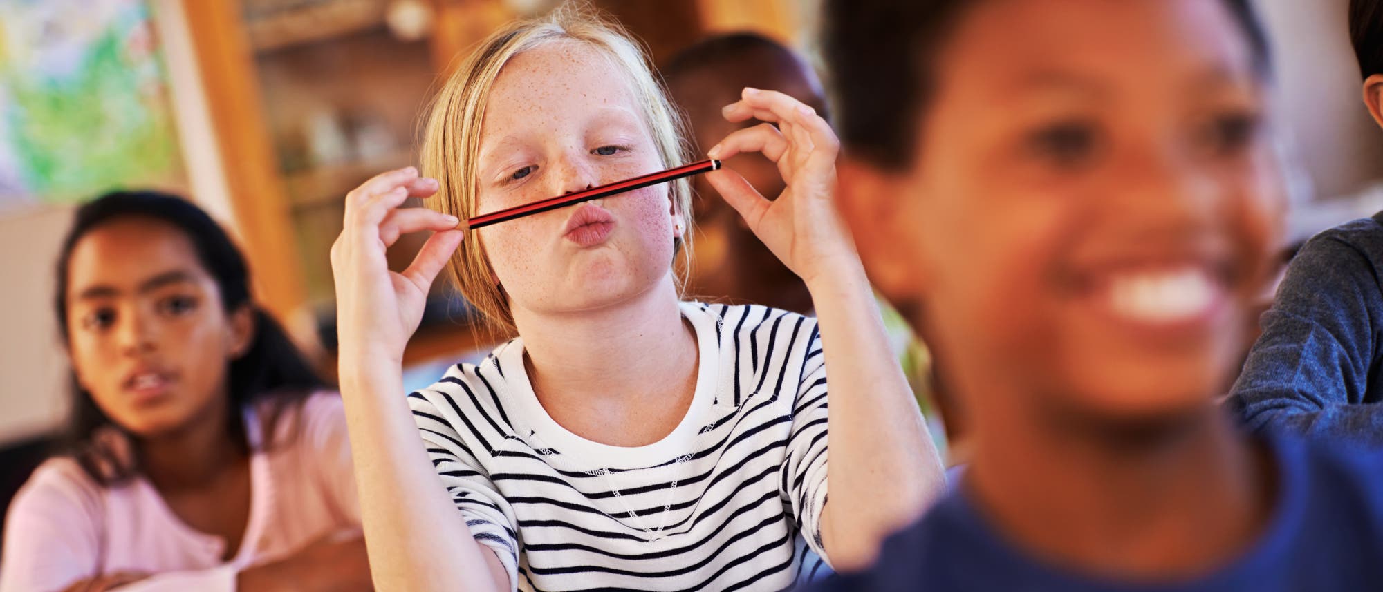 M&auml;dchen im Klassenzimmer spielt mit Stift