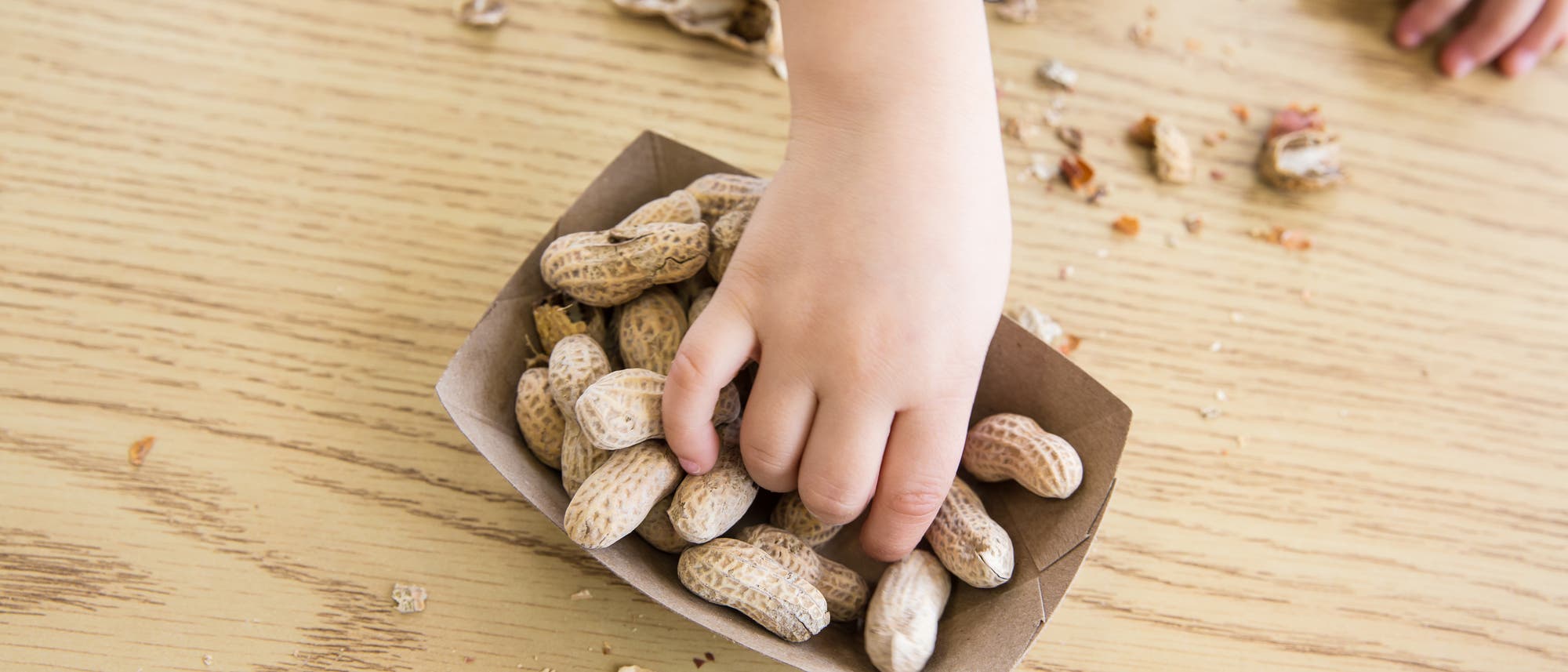 Kind greift nach Erdnüssen