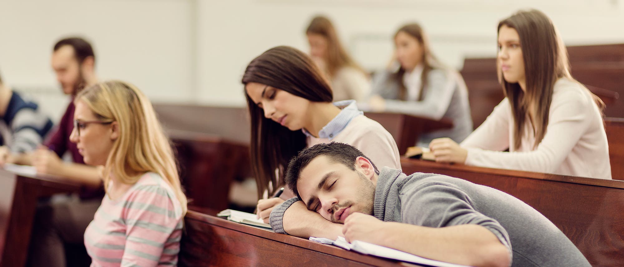 Student liegt schlafend in der Vorlesung