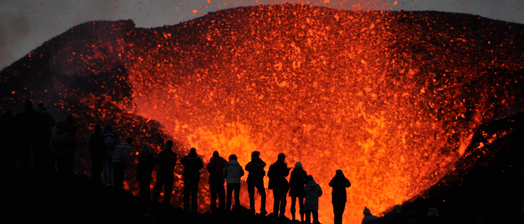 Eine Gruppe von lebensmüden Knalltüten steht direkt am Krater eines aktiven Vulkans.