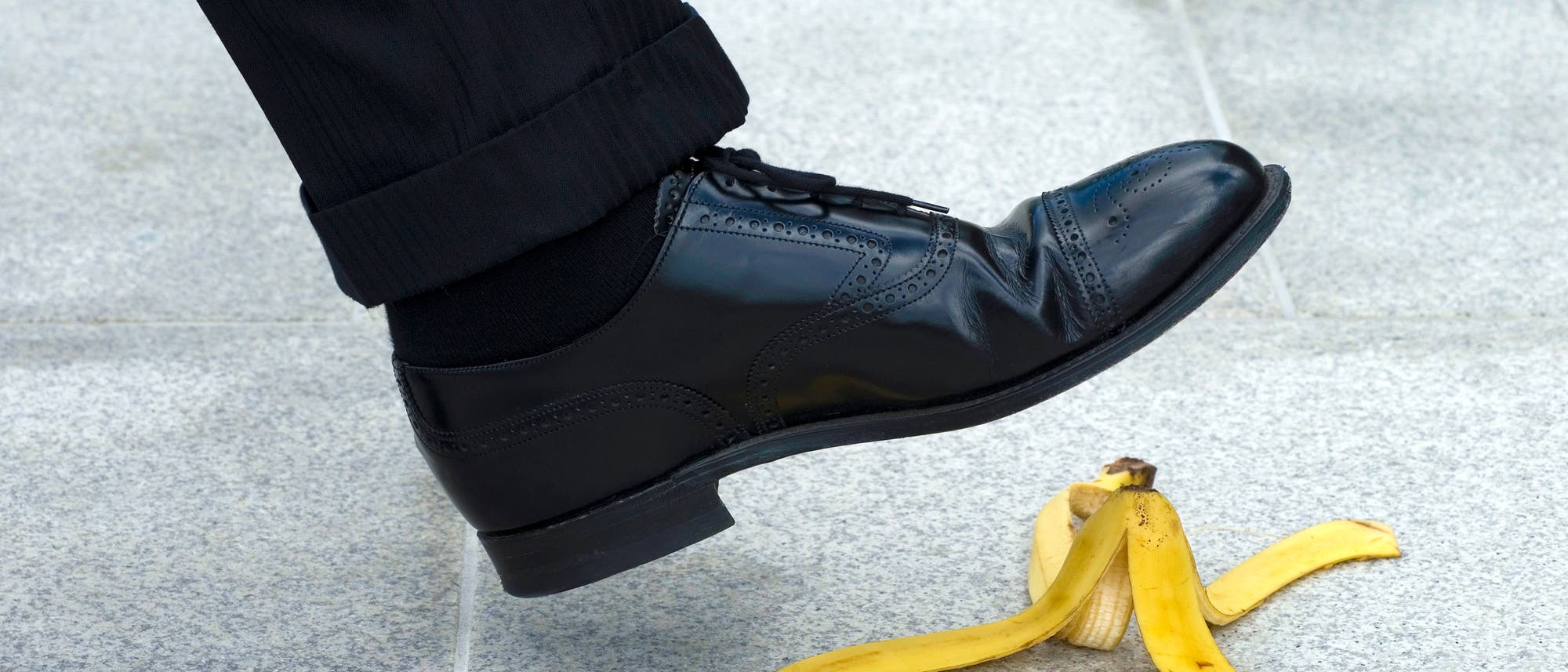 Der Fuß eines Mannes, der im Begriff ist, auf einen Bananenschale zu treten.