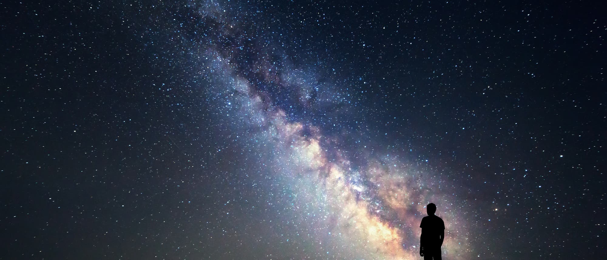 Silhouette eines Menschen, der nachts die Milchstraße betrachtet.