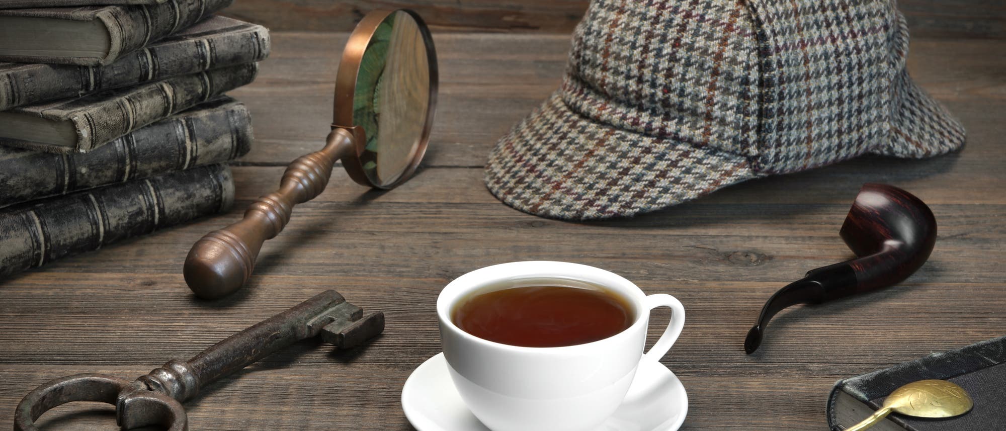 Die für den literarischen Meisterdetektiv Sherlock Holmes typischen Utensilien Pfeife, Lupe und karierte Mütze. Aus mysteriösen Gründen nicht im Bild: das Opium.