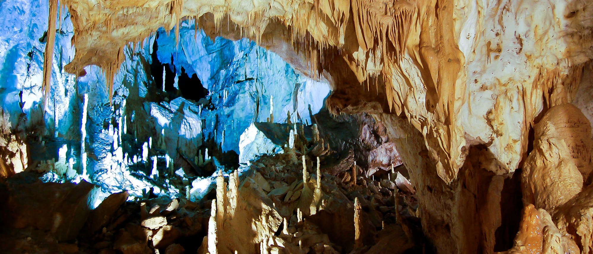 Eine hohe Tropfsteinhöhle spektakulär ausgeleuchtet.