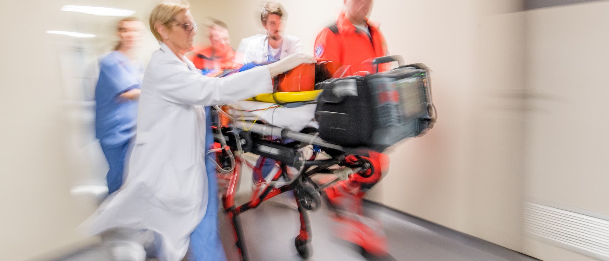 Einlieferung eines Notfalls im Krankenhaus. Notärzte und Krankenhauspersonal transportieren Verletzten auf einer mobilen Liege