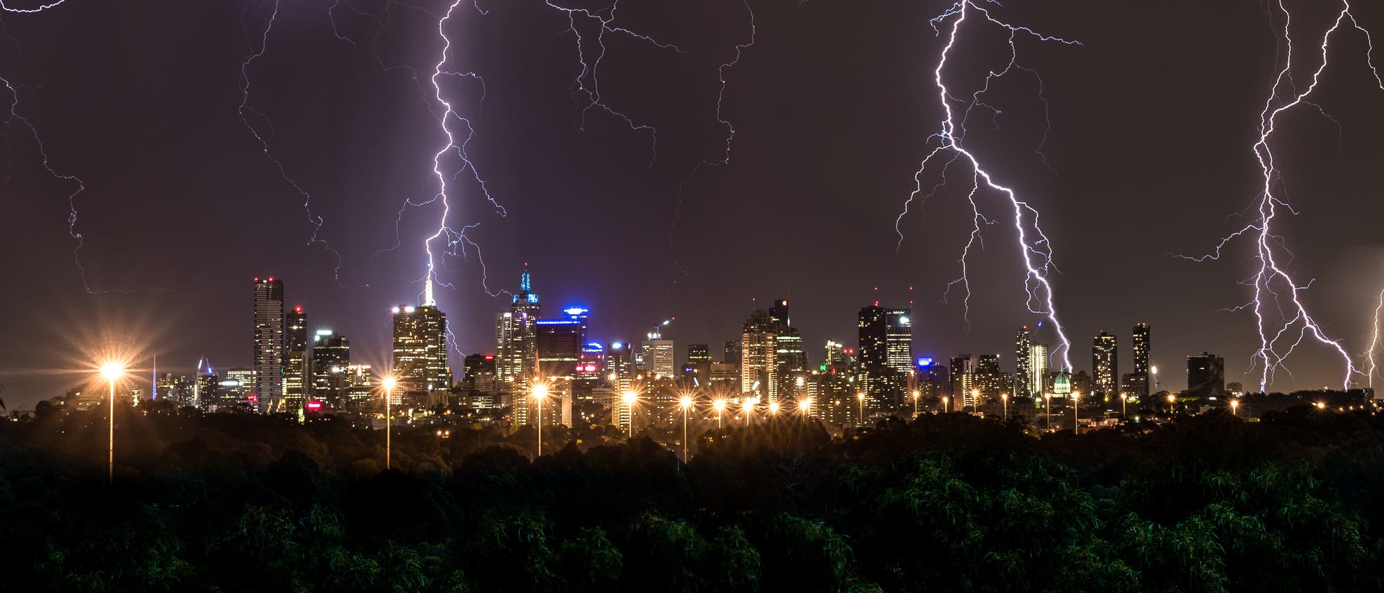 Blitze über der nächtlich erleuchteten Großstadt Melbourne.