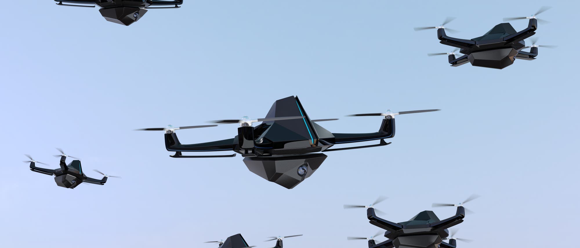 Mehrere bedrohlich aussehende Quadcopter-Drohnen vor blauem Himmelshintergrund.