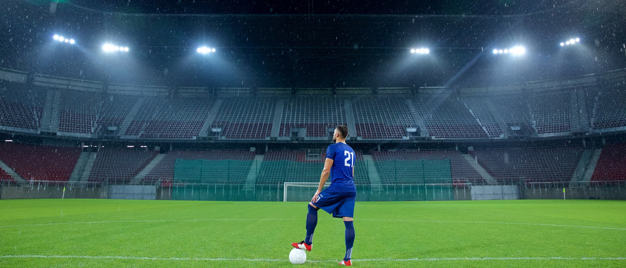 Ein Fußballer steht allein in einem leeren Stadion