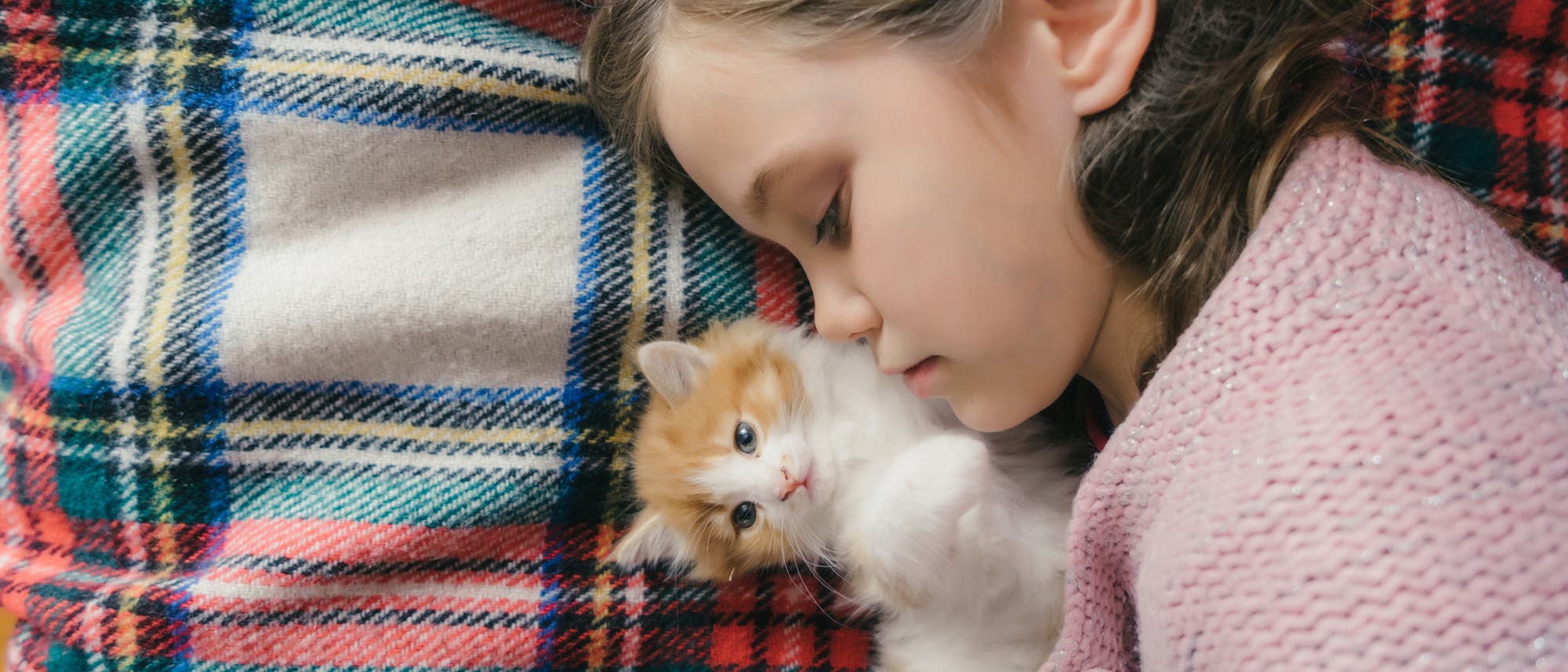 Mädchen mit jungem Kätzchen auf einer Decke