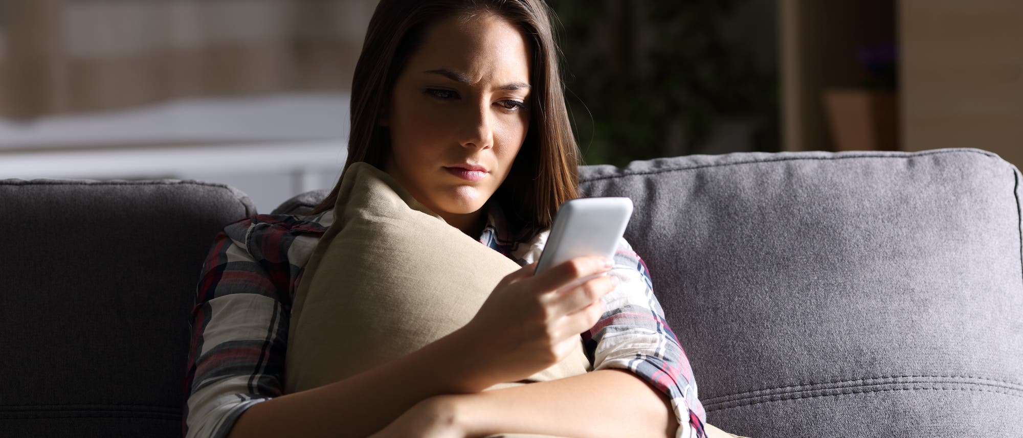 Frau sitzt im Schatten und liest Nachrichten auf ihrem Handy