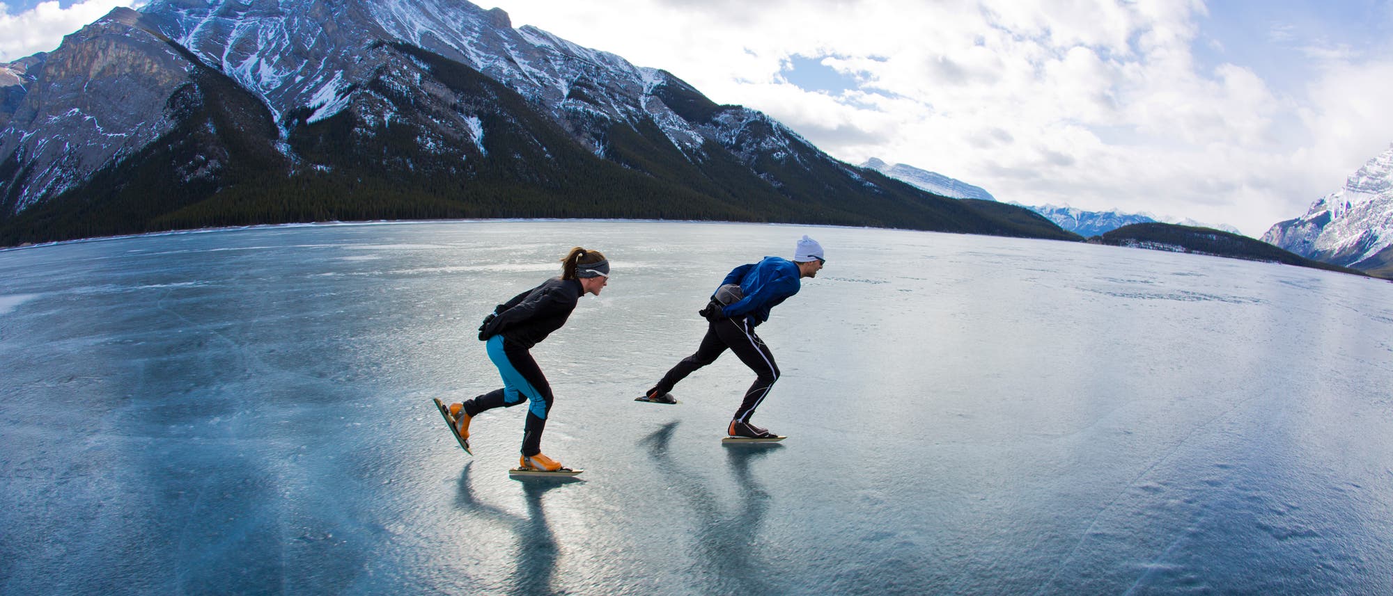 Zwei Schlittschuhläufer gleiten auf einem zugefrorenen See.