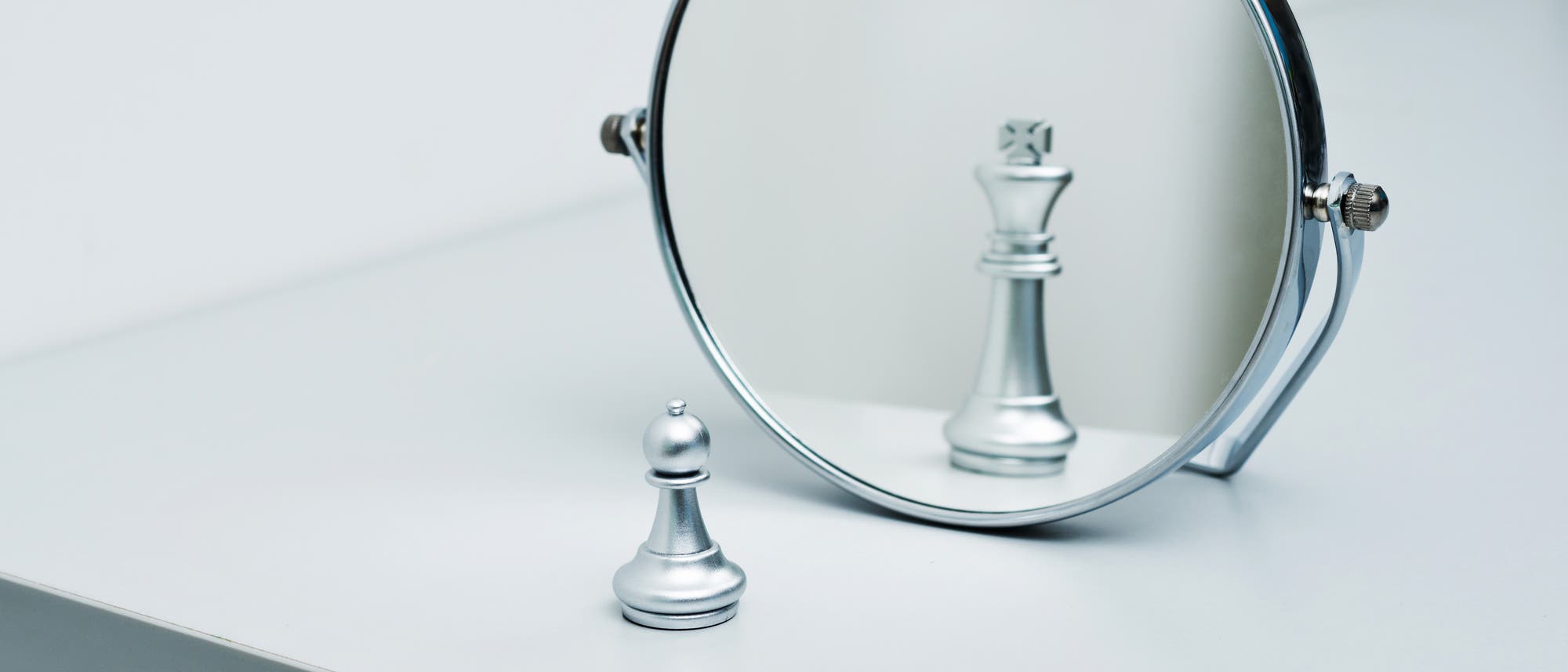 Eine Bauer-Schachfigur sieht sich in einem Spiegel als König. 