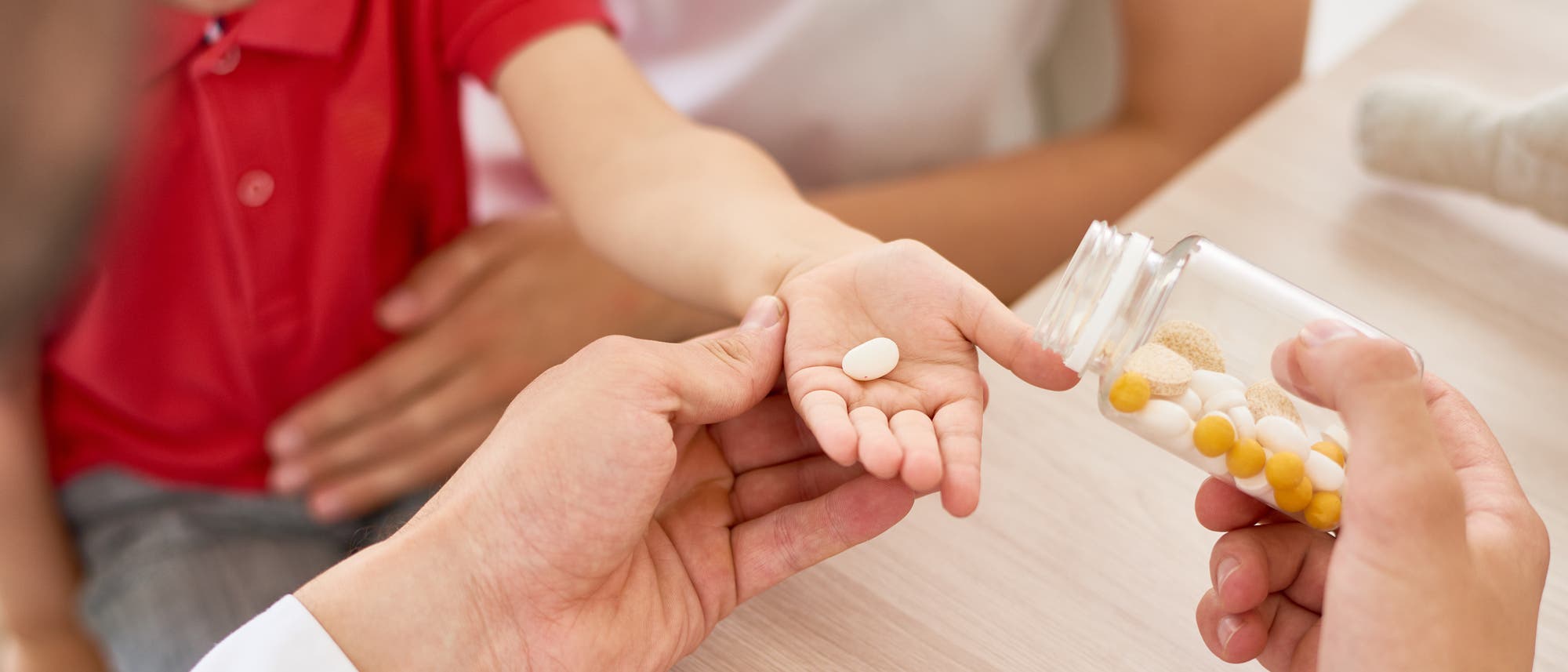 Ein Arzt gibt einem Kind eine Tablette in die Hand.
