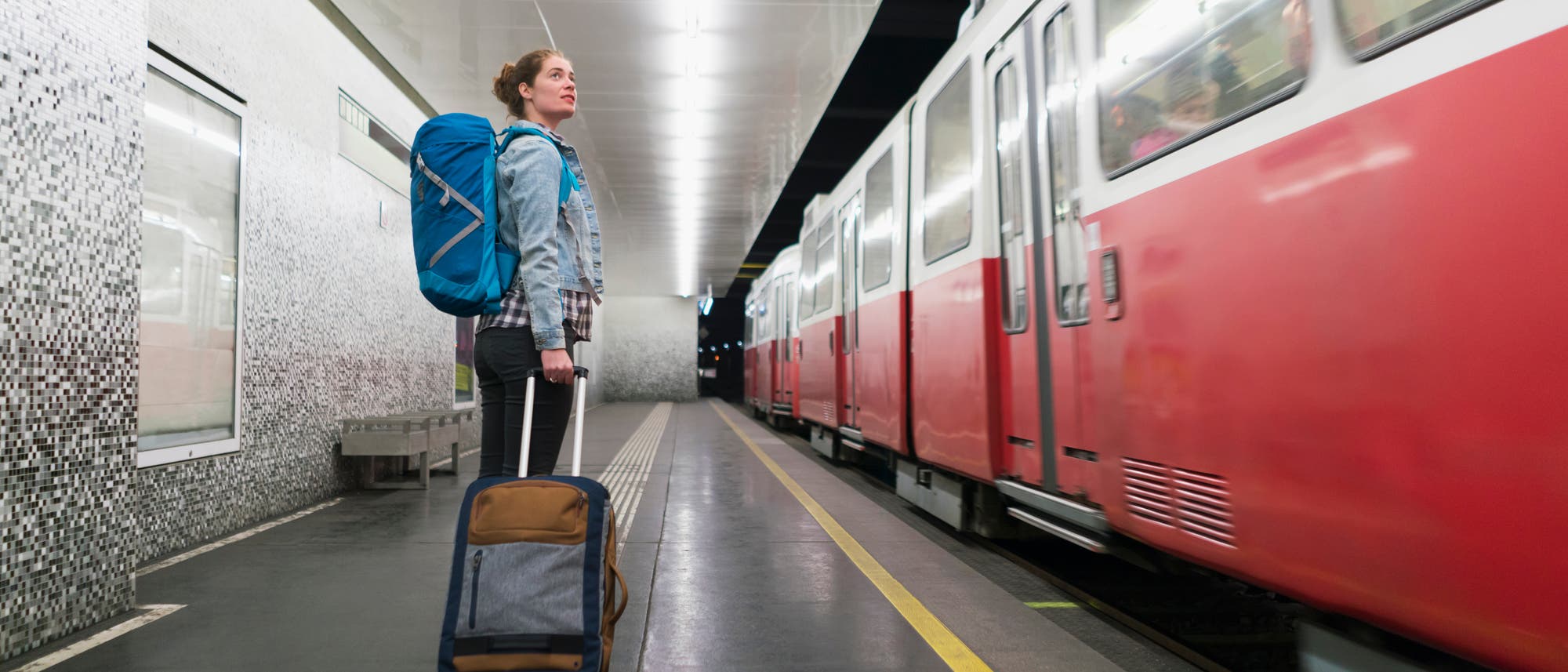 Ein Reisender wartet mit seinem Gepäck auf den Zug.