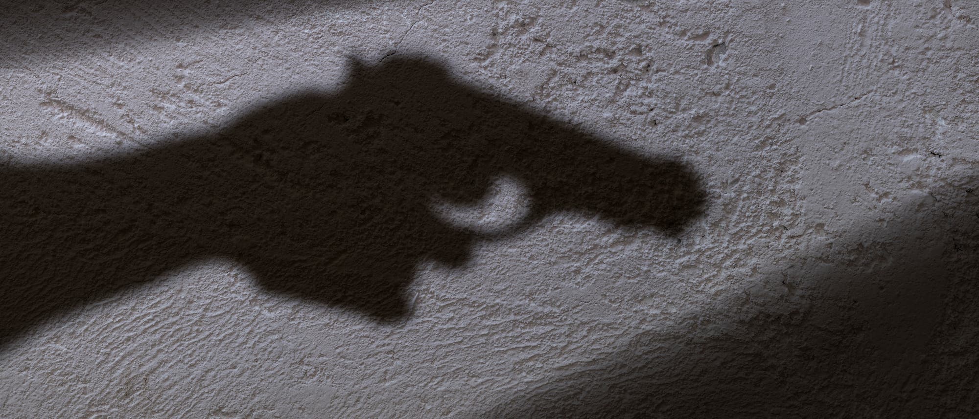 Schatten einer Pistole an der Wand