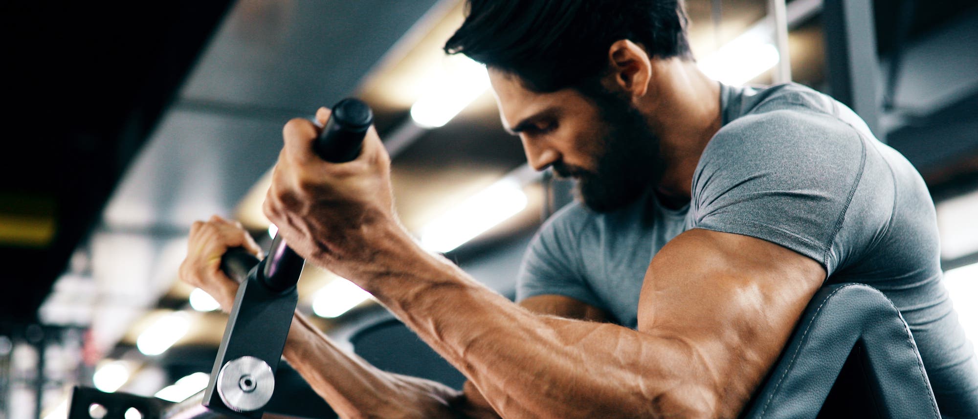 Äußerst muskulöser Mann trainiert seine Arme am Gerät