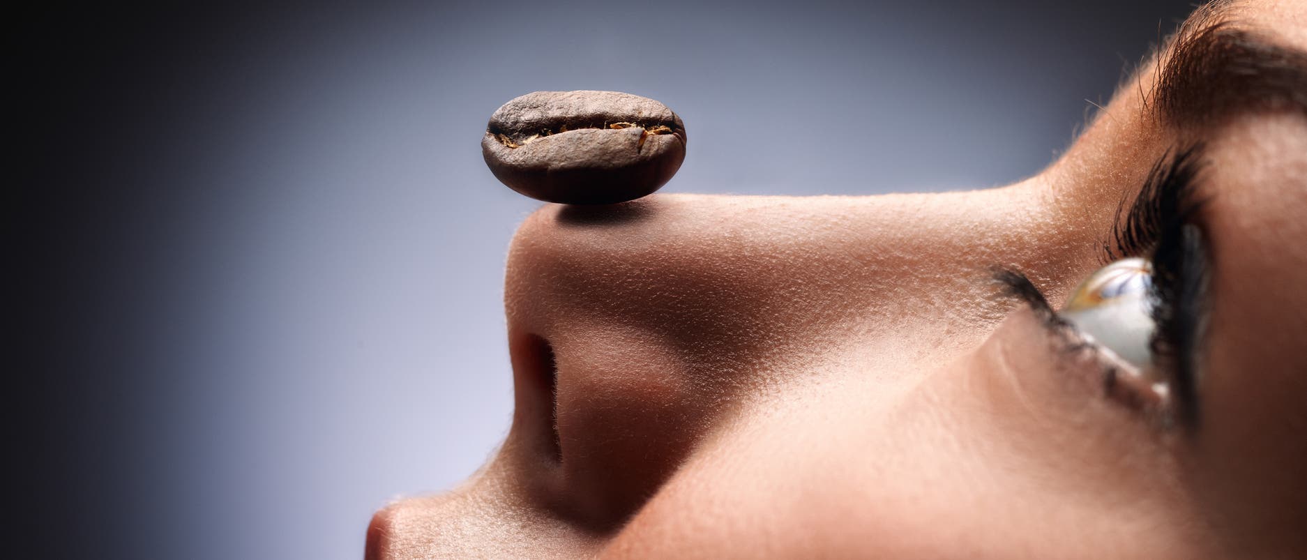 Eine Frau balanciert eine Kaffeebohne auf der Nase. Warum sie das tut, bleibt ihr Geheimnis, aber es sieht sehr anmutig aus.