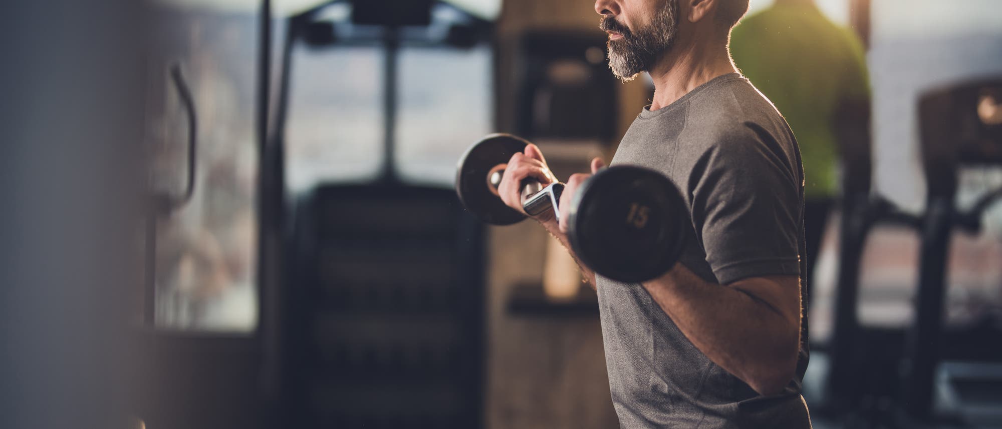 Ein älterer Mann trainiert mit einer Hantel seine Armmuskulatur im Fitness-Studio. Ein älterer Mann trainiert mit einer Hantel seine Armmuskulatur im Fitness-Studio.