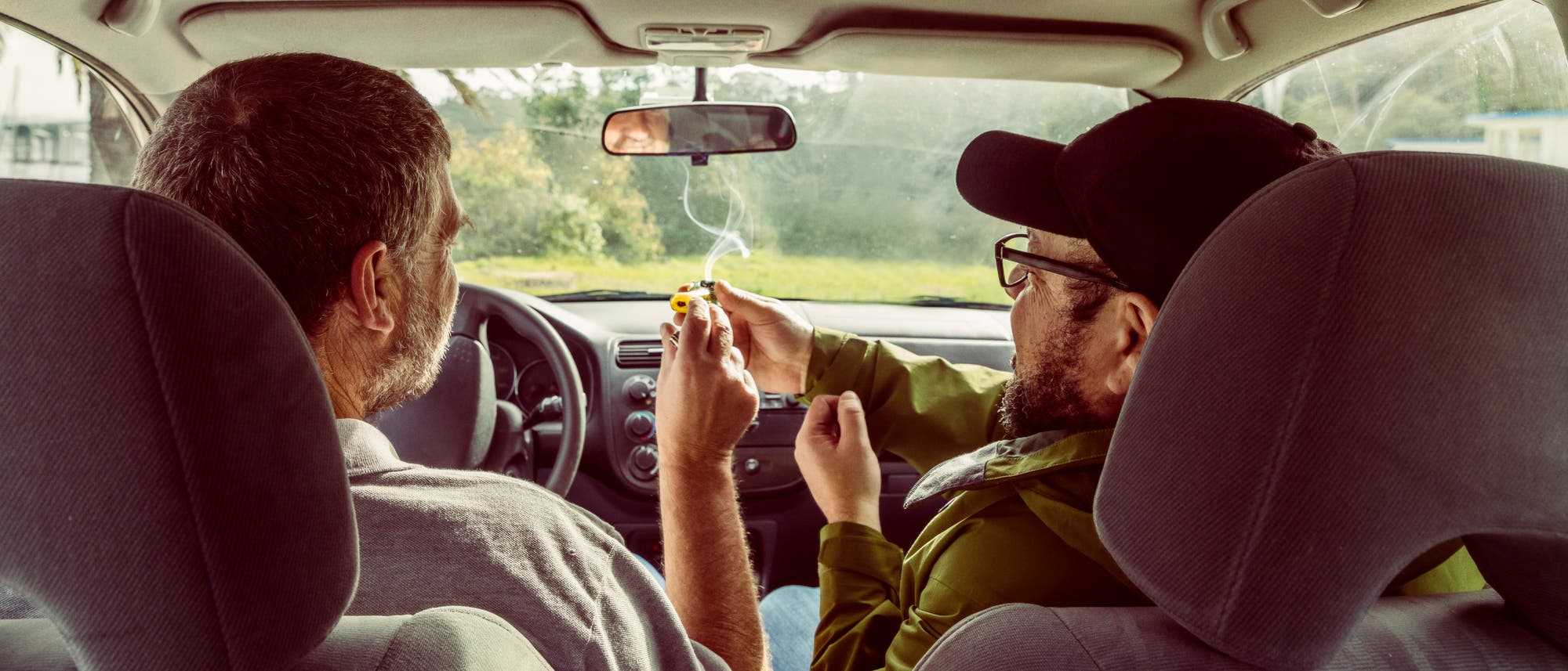 Zwei Männer beim vergnügten Cannabiskonsum im Auto