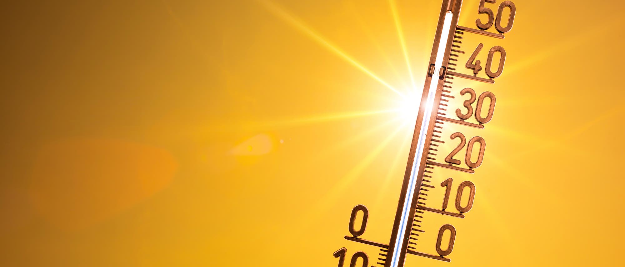 Ein Thermometer vor der Sonne in einem orangefarbenen Himmel zeigt 35 Grad.