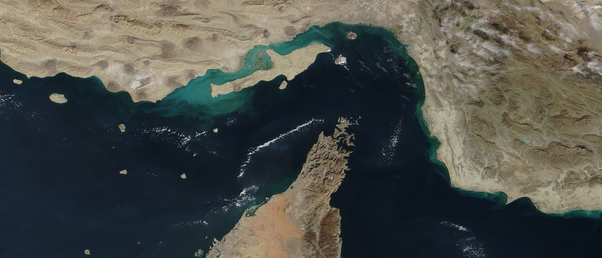 Satellitenbild der Stra&szlig;e von Hormus, das die geografische Lage zwischen dem Iran im Norden und der Arabischen Halbinsel im S&uuml;den zeigt. Die Wasserstra&szlig;e verbindet den Persischen Golf mit dem Golf von Oman. Deutlich sichtbar sind die K&uuml;stenlinien und die umgebenden W&uuml;stenlandschaften. Das Bild hebt die strategische Bedeutung der Meerenge hervor, die ein wichtiger Schifffahrtsweg ist.