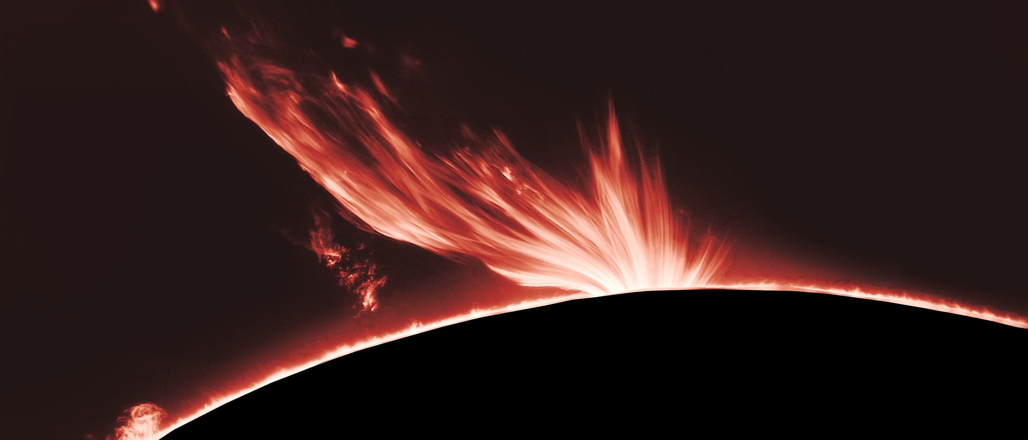 Eine beeindruckende Aufnahme einer Sonneneruption, die von der Oberfl&auml;che der Sonne aufsteigt. Die Eruption zeigt leuchtende, flammenartige Strukturen, die sich in den Weltraum erstrecken. Der dunkle Hintergrund hebt die Intensit&auml;t der gl&uuml;henden Materie hervor. Dieses astronomische Bild veranschaulicht die dynamische Aktivit&auml;t der Sonnenoberfl&auml;che.