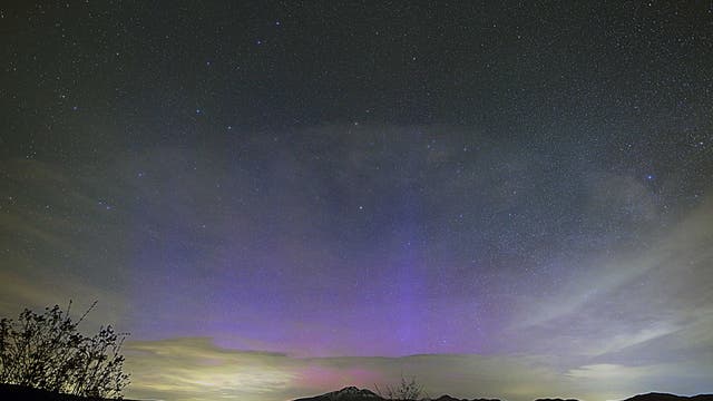 Am Nachthimmel ist ein großflächiges blaues Licht zu sehen, kleinere Bereiche sind auch magentafarben. Einzelne Sterne sind in den nachtschwarzen Bereichen des Himmels erkennbar.