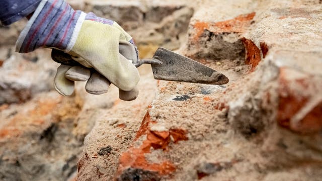 Babis Papasavvas, Restaurator und Grabungshelfer, befreit im archäologischen Grabungsfeld im Mühlendamm am Ort des historischen Molkenmarktes mit einer Kelle Steine von Sand und Schutt