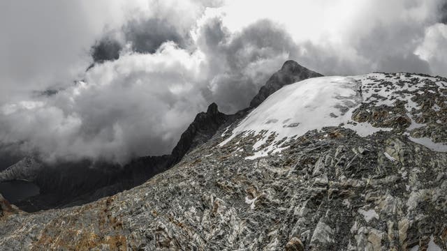 Archivbild des Humboldt-Gletschers in Venezuela, als dieser noch als Gletscher galt: eine kleine weiße Eisfläche in der rechten Bildmitte, umgeben von grauem Gestein. Im Hintergrund ein Berggipfel, der von weißen Wolken umgeben ist.