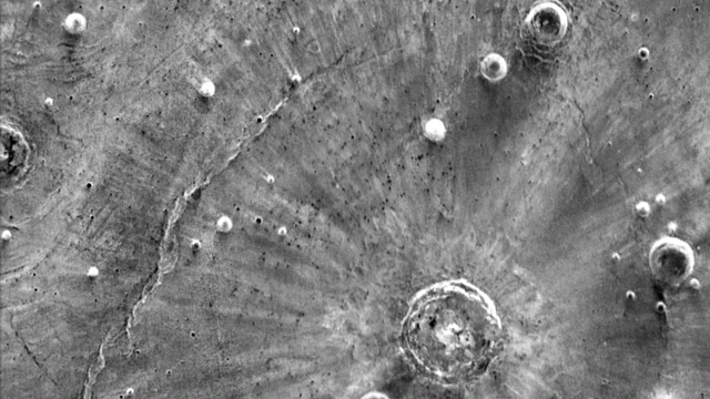 Infrarotaufnahme von der Oberfläche des Mars mit hellen Streifen, die paarweise vom Einschlagort wegzeigen