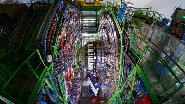 Blick von oben in die Kaverne des gewaltigen CMS-Detektors, in dessen Zentrum mehrere Personen Bauteile montieren