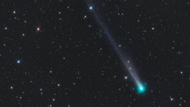 Ein leuchtender Komet mit einem langen, schimmernden Schweif zieht durch ein sternenübersätes Universum. Der Komet strahlt in einem intensiven Türkis, während sein Schweif in einem sanften Blau verläuft. Umgeben von zahlreichen funkelnden Sternen, hebt sich der Komet deutlich vom dunklen Hintergrund des Weltraums ab.
