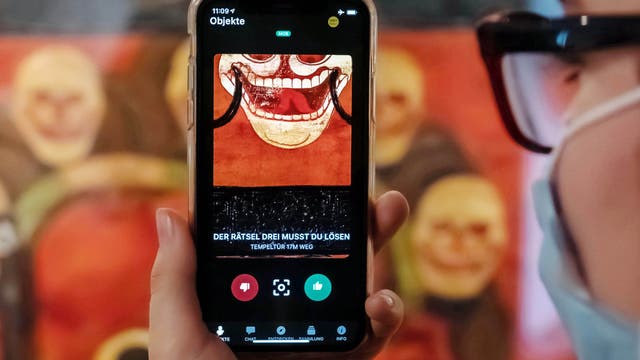 Im Badischen Landesmuseum wird vor einer Tempeltür aus Tibet aus dem 19. Jahrhundert auf einem Smartphone eine App gezeigt, mit der Museumsbesucher Kontakt zu Ausstellungsobjekten aufbauen können.