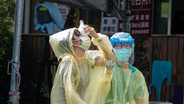 Nachdem sie in einem Testzentrum in New Taipei City auf Covid-19 getestet wurde, hält eine Person einen Eisbeutel gegen ihre Nase.