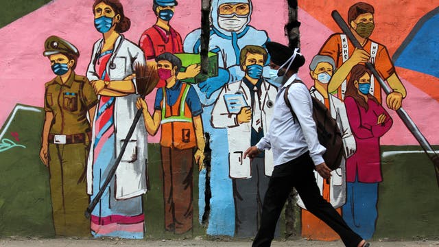 Ein Mann geht in Neu-Delhi, Indien, an einem Graffiti vorbei, das die Mitarbeiter des Gesundheitswesens würdigt.