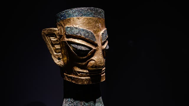 Spitze Augen, große Ohren, kantige Gesichtszüge – der Kopf aus Bronze zeigt die für die Sanxingdui-Kultur typischen Stilformen. Das Gesicht ist mit einer dünnen Goldfolie belegt. Die Skulptur kam in einer von acht großen Opfergruben ans Licht.