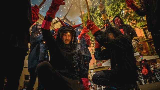 Feuerläufer der katalonischen 'Diables Vell de la Gracia' in Teufelskostümen tanzen zu traditionellen Trommeln und entzünden Feuerwerk.