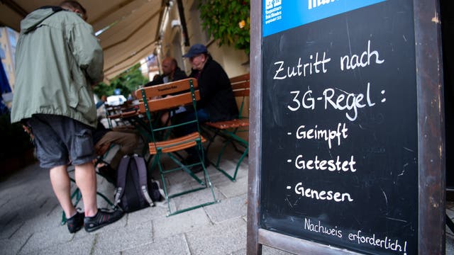 Ein Aufstellschild mit Hinweis auf die 3G-Regeln, im Hintergrund der Außenbereich eines Cafés.