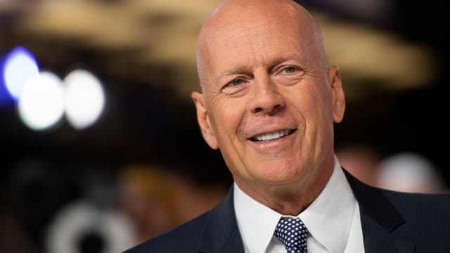 Porträtfoto von Schauspieler Bruce Willis in schwarzem Anzug, weißem Hemd und mit Krawatte