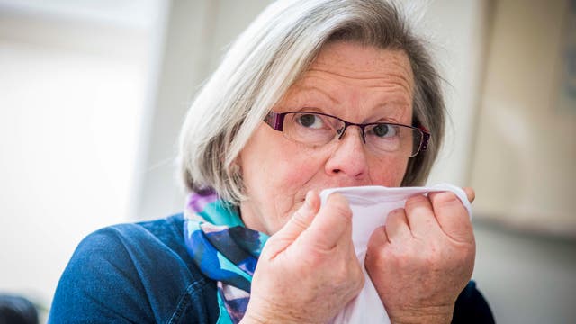 Die pensionierte Krankenschwester Joy Milne riecht an einem Stück Kleidung.