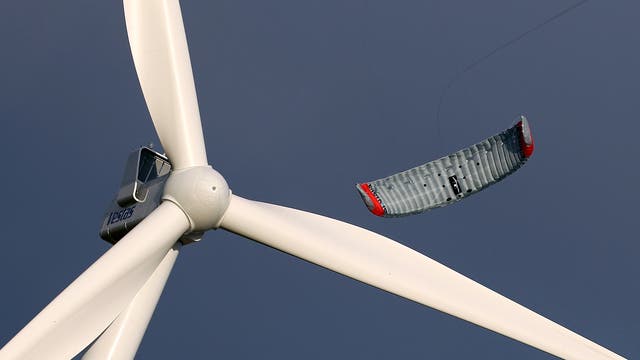 Der Prototyp eines Windenergie-Drachens hinter dem Rotor eines stationären Windrads.