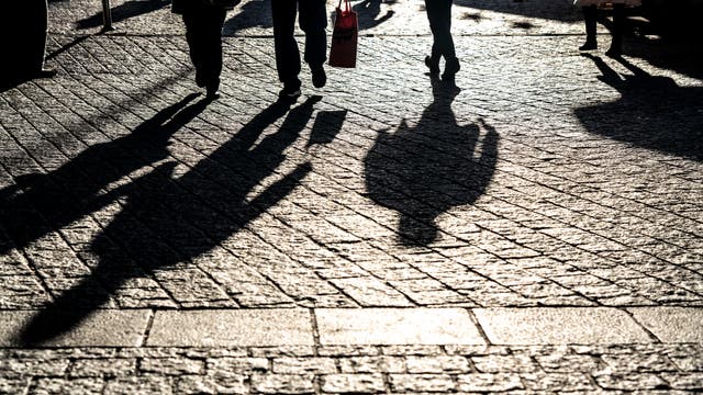 Die Schatten von drei Fußgängern in Dortmund. 