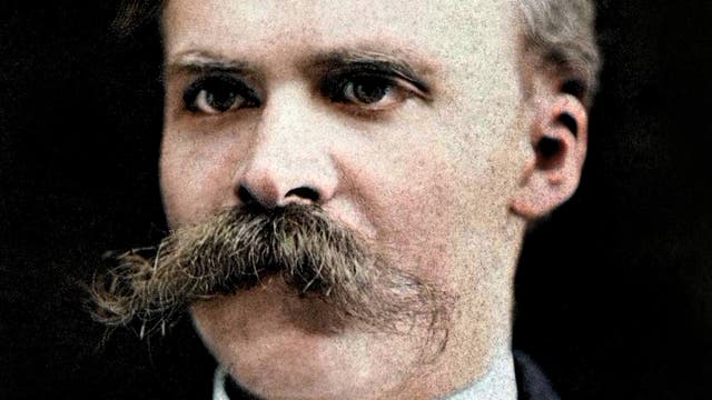 Ein Porträtfoto eines Mannes mit einem markanten Schnurrbart. Er trägt einen Anzug mit Hemd und Fliege. Der Hintergrund ist dunkel, wodurch der Fokus auf das Gesicht des Mannes gelegt wird.