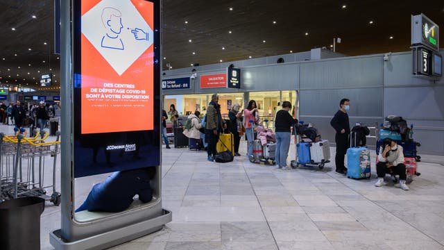 Reisende aus China stehen in einer Schlange am Pariser Flughafen Charles-de-Gaulle