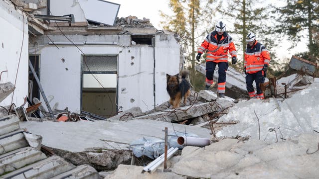 Ein Mitglied der Rettungshundestaffel läuft mit einem Hund über Trümmer