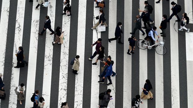 Menschen überqueren eine Straße in einem Einkaufsviertel in Tokio.